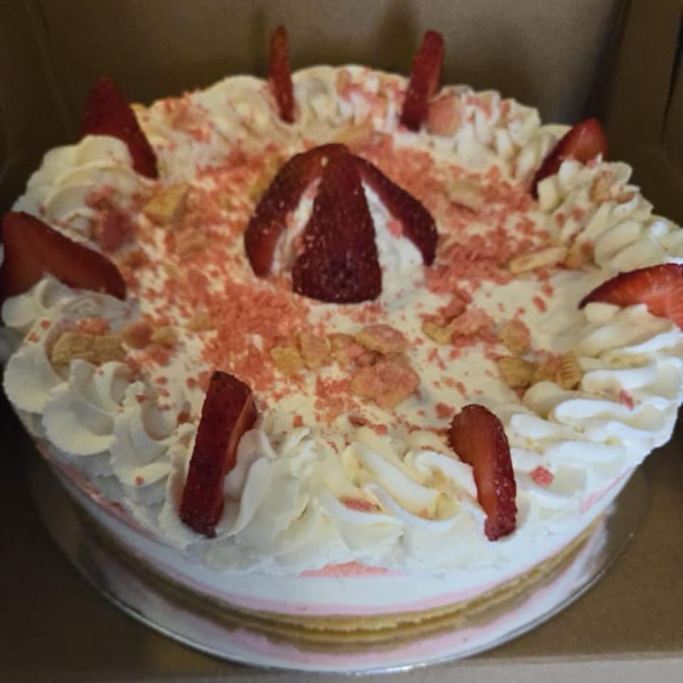 A strawberry crunch cake with whipped cream, strawberry slices, and pink crumble topping.